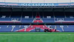 Pelouse du Parc des princes avec les sièges colorés aux couleurs du PSG et formant l'emblème du club. Un agent s'occupe de l'entretien de la pelouse
